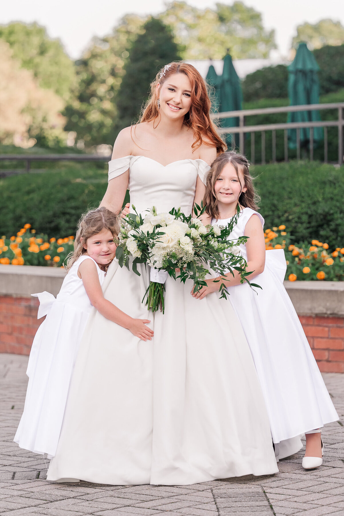 A smiling redheaded bride with her two loving  flower girls enjoying their Raleigh wedding photography session by JoLynn Photography