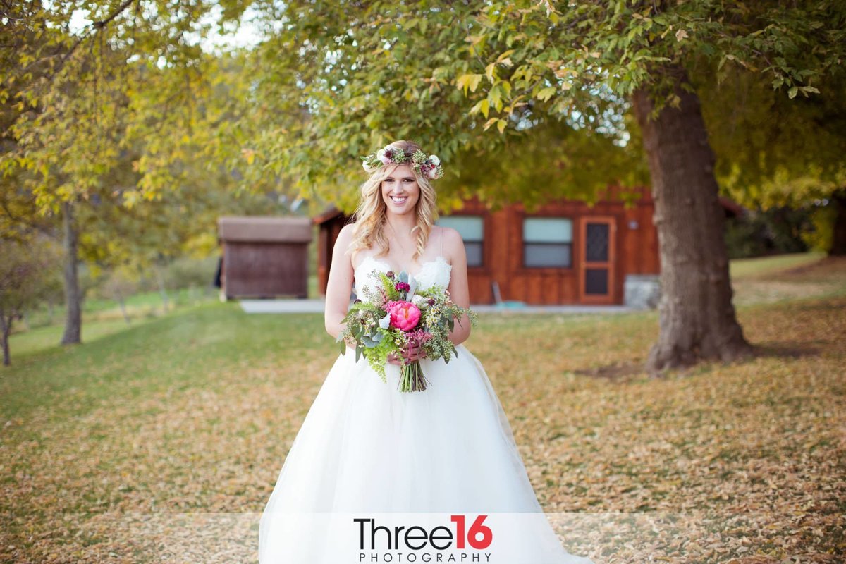 Bride poses for camera in front of barn