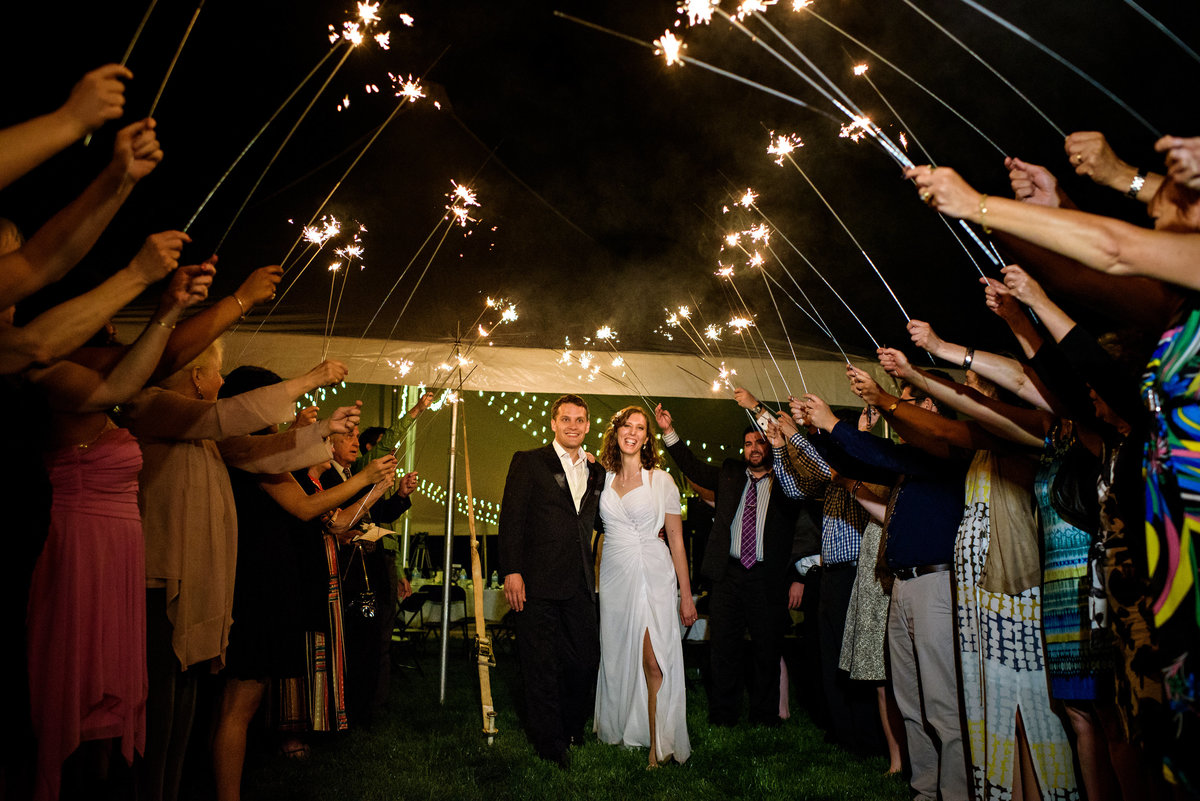 Wedding guests hold sparklers over a bride and groom as they leave the reception in bucks county PA.