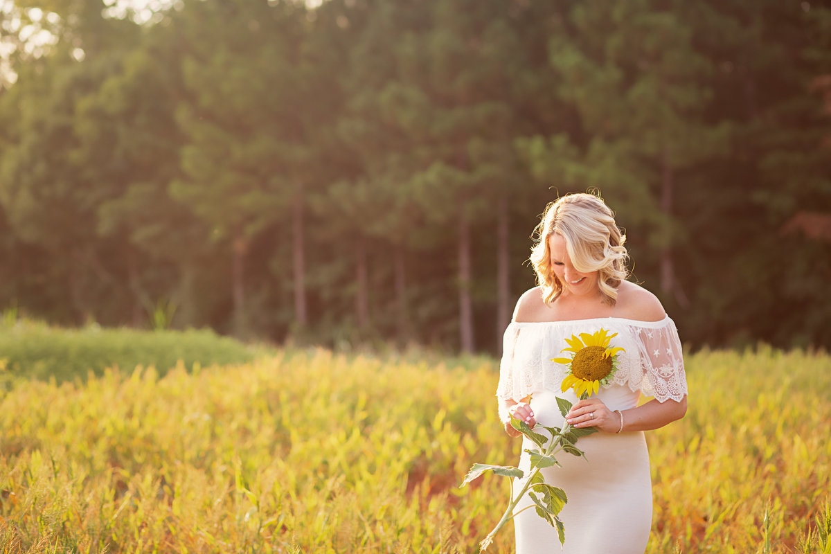 Expecting mom holding sunflower white maternity gown