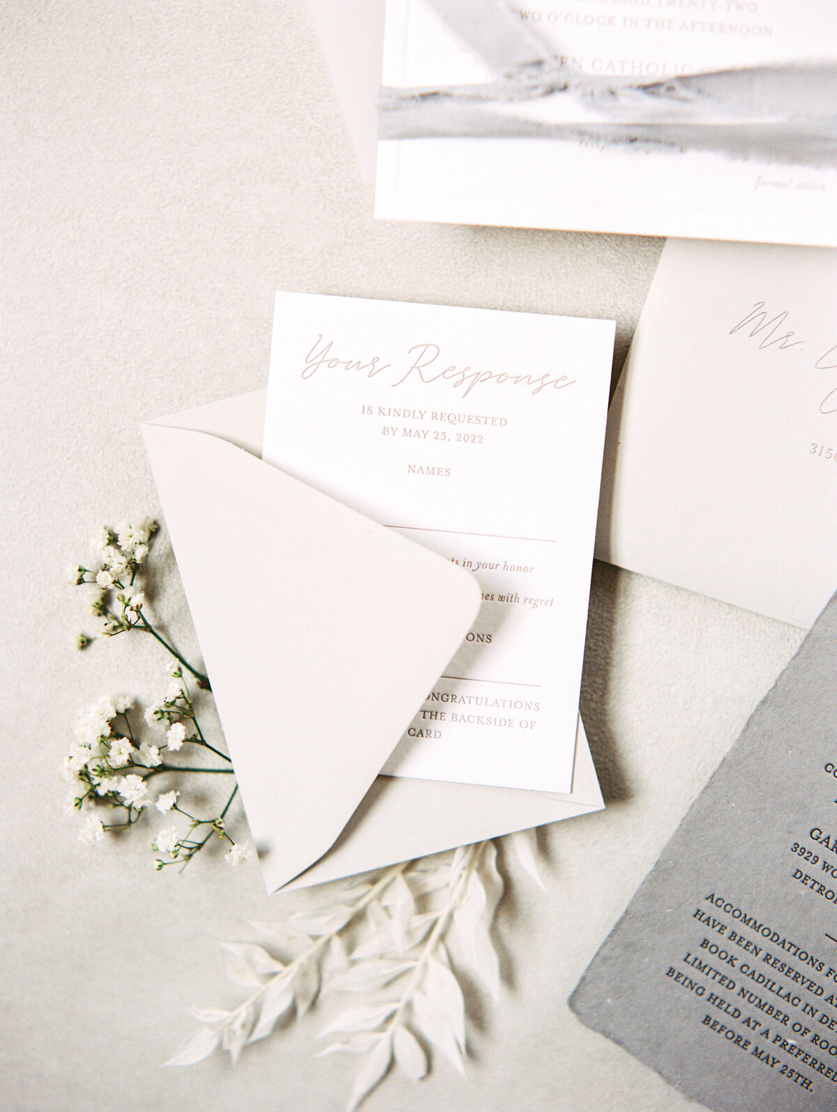 a custom wedding invitation suite from alyssa amez design custom wedding stationery and signage designer against a white background with a white envelope white flowers