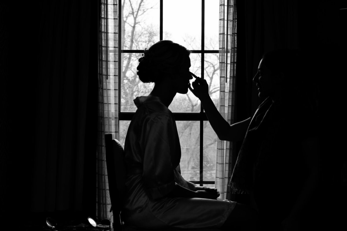 Bride getting makeup done in black and white at The Inn at Fox Hollow