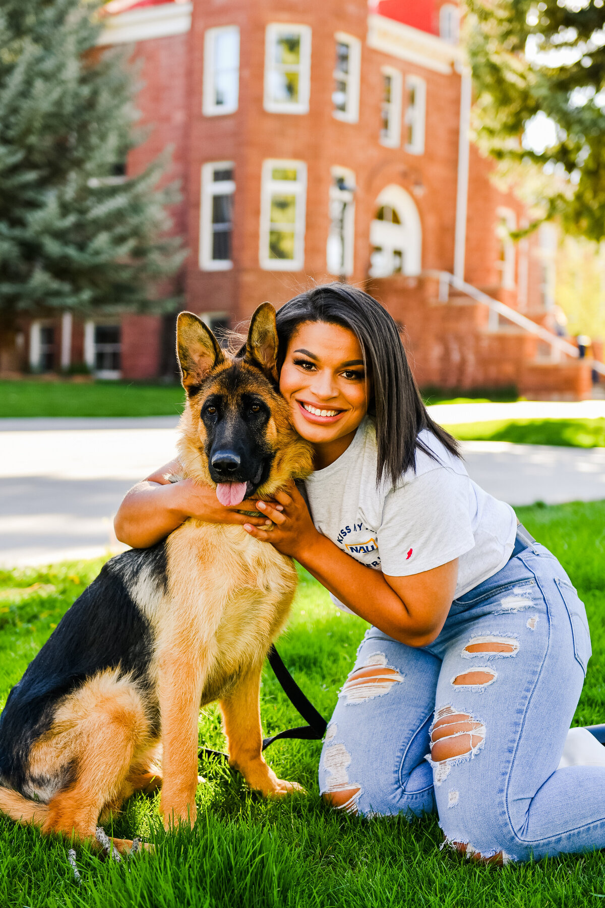 NAU senior graduation photographer holding dog looking at camera kneeling at Old Main Northern Arizona University
