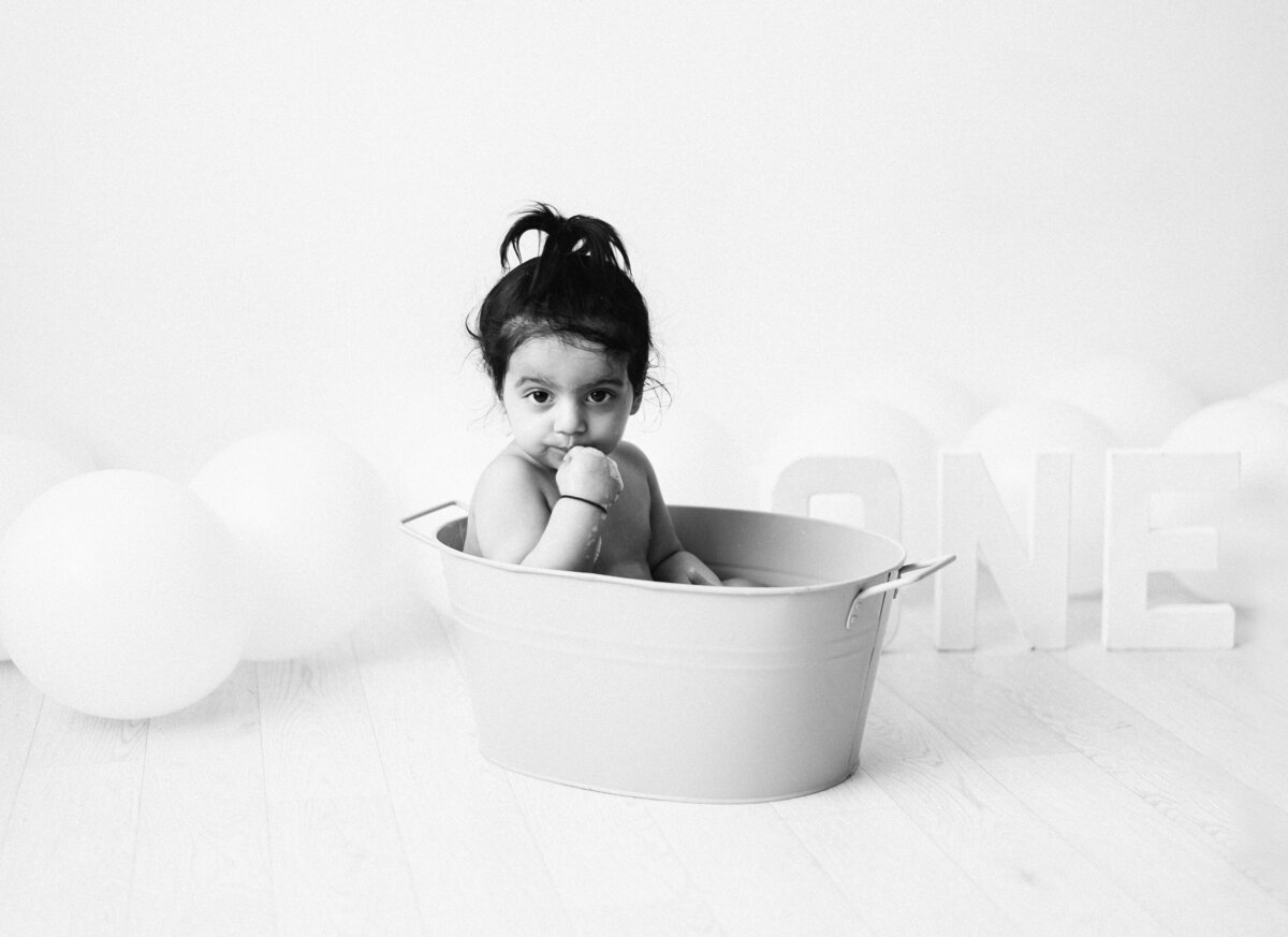 baby girl smiling in a tub at west sussex cake smash photoshoot