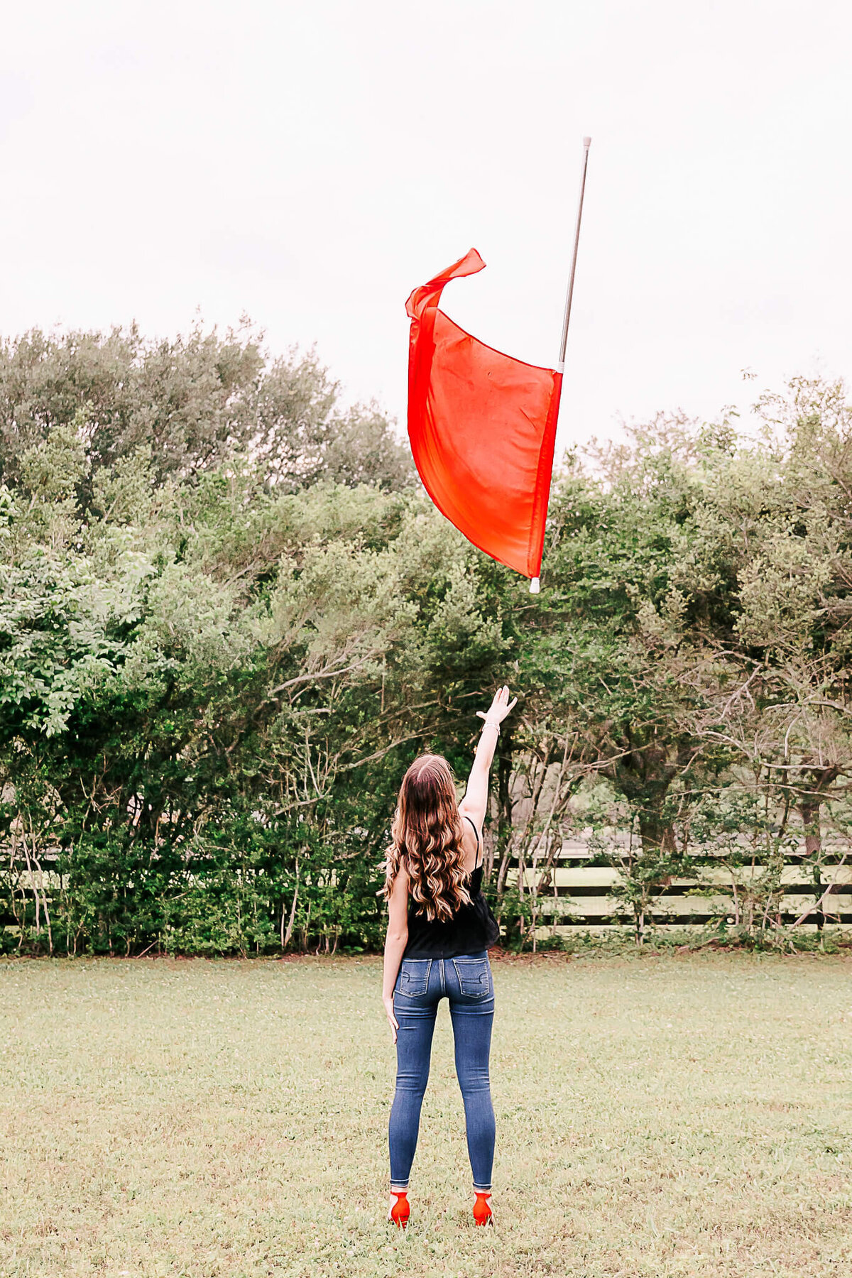 Color guard graduate throwing flag in the air wearing red shoes