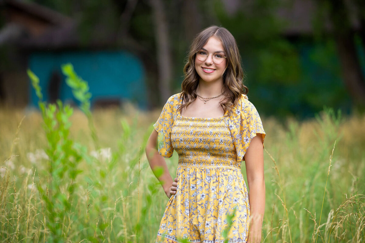 teenage girl in yellow sun dress standing in a tall grassy field