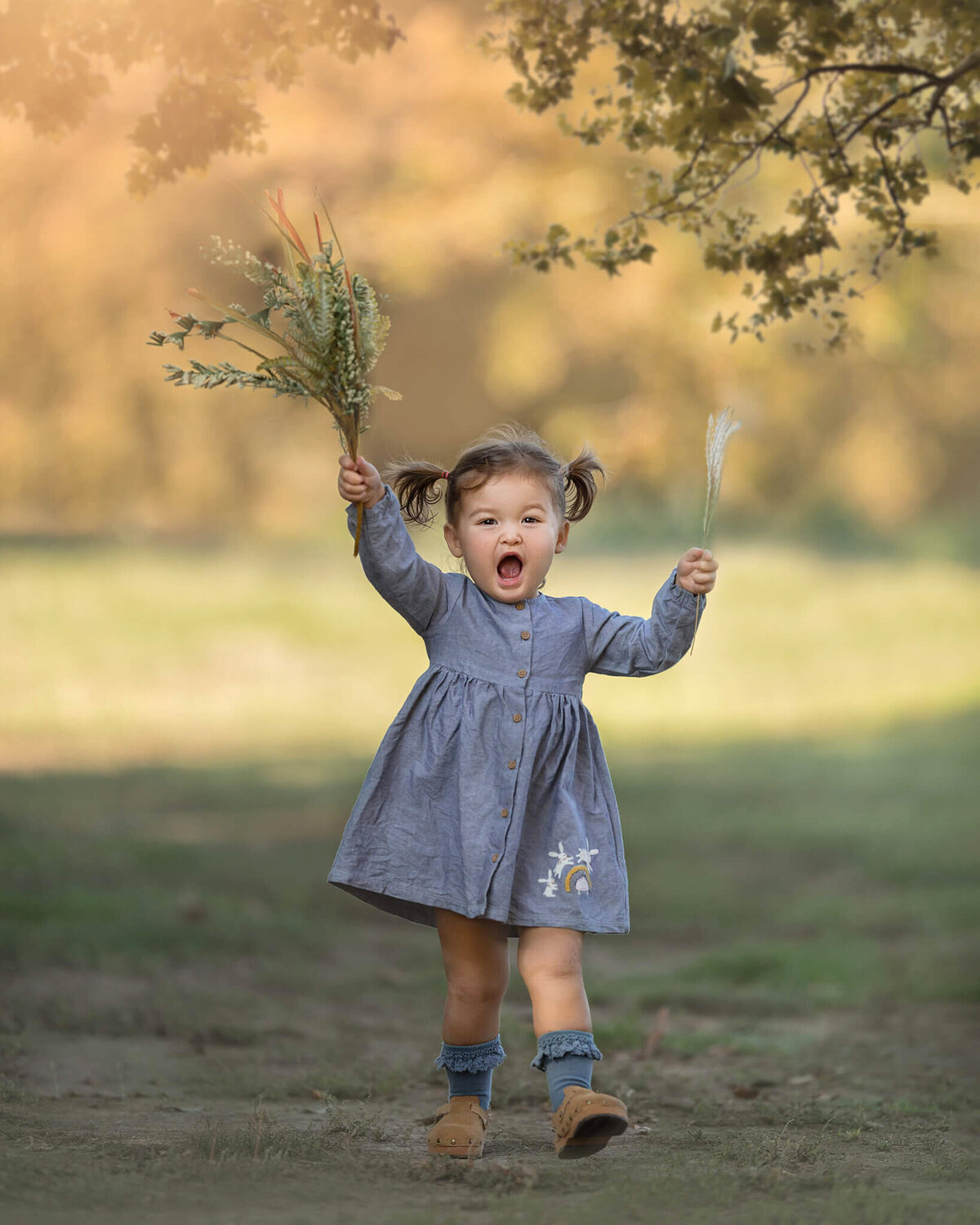 Little girl holding flowers and laughing runnign towards the camera - Los Angeles Children’s Photographer