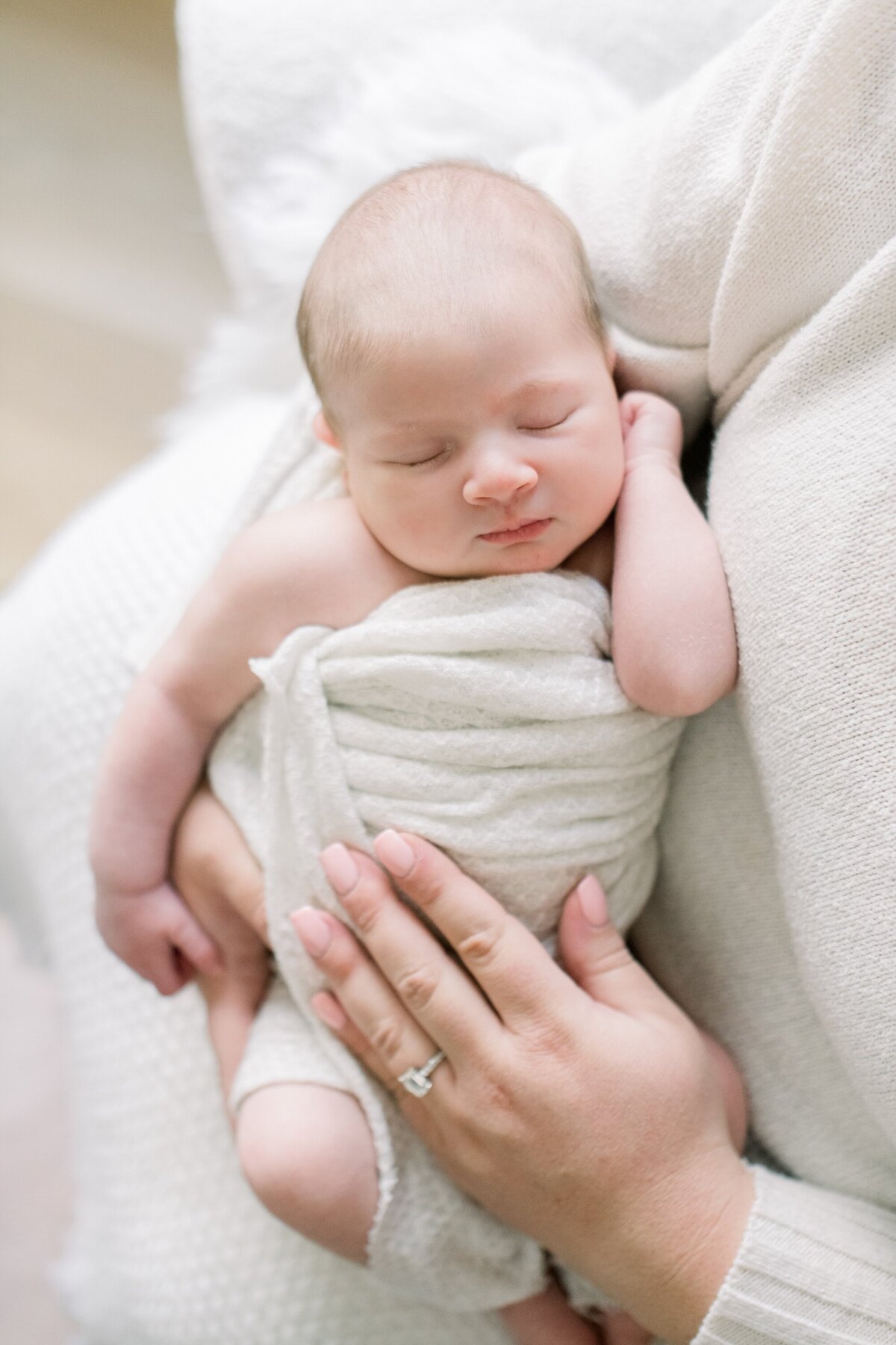 mom holding baby in white swaddle blanket by westchester newborn photographer nicole detone