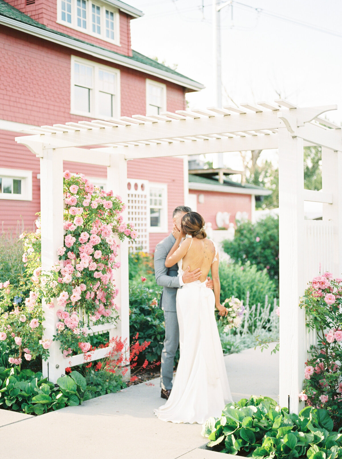 Wedding couple kissing underneath flower trellis