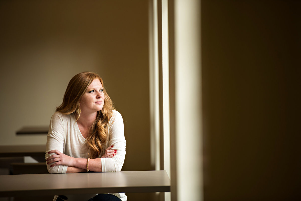 A red head sits at a desk in front of a window.