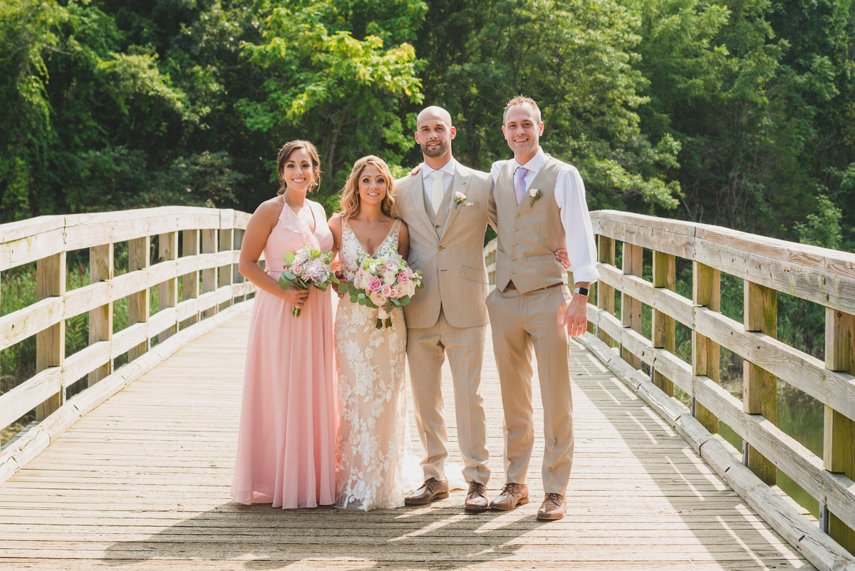 photo of bride and groom with maid of honor and best man on the bridge from beach wedding at Pavilion at Sunken Meadow
