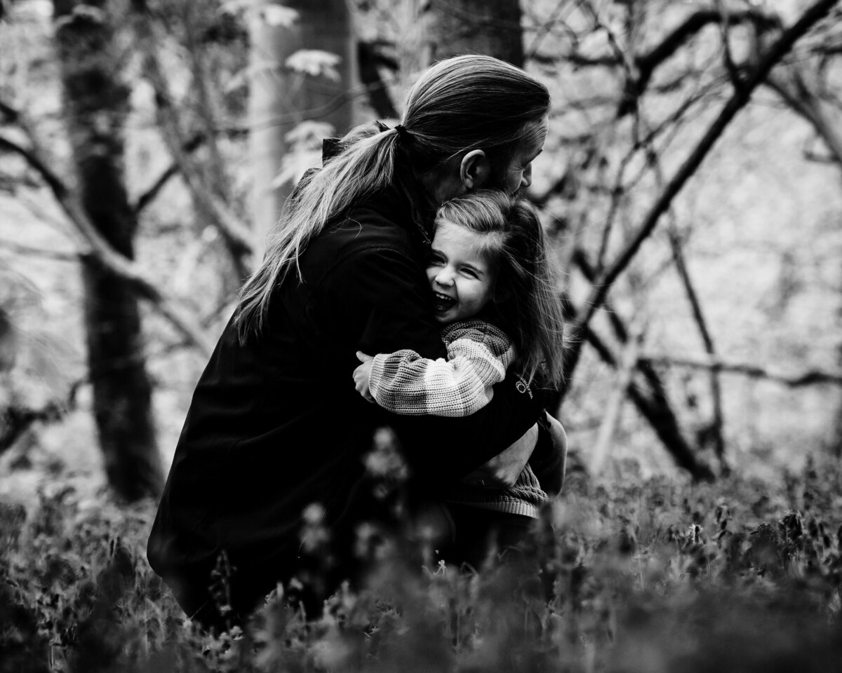 Dad cuddling his daughter in the bluebells black and white image