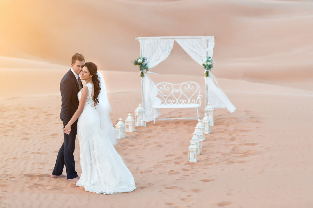 Wedding couple standing in front of wedding arch during desert elopement photoshoot organized by Lovely & Planned