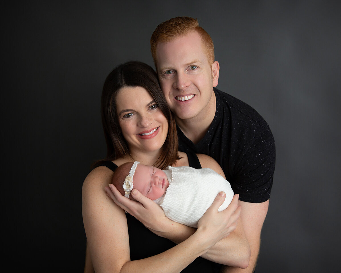 Mom and dad holding newborn for professional portrait in Pittsburgh photography.