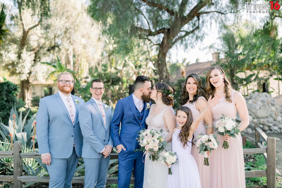 Bride and Groom kiss while posing with Bridal Party