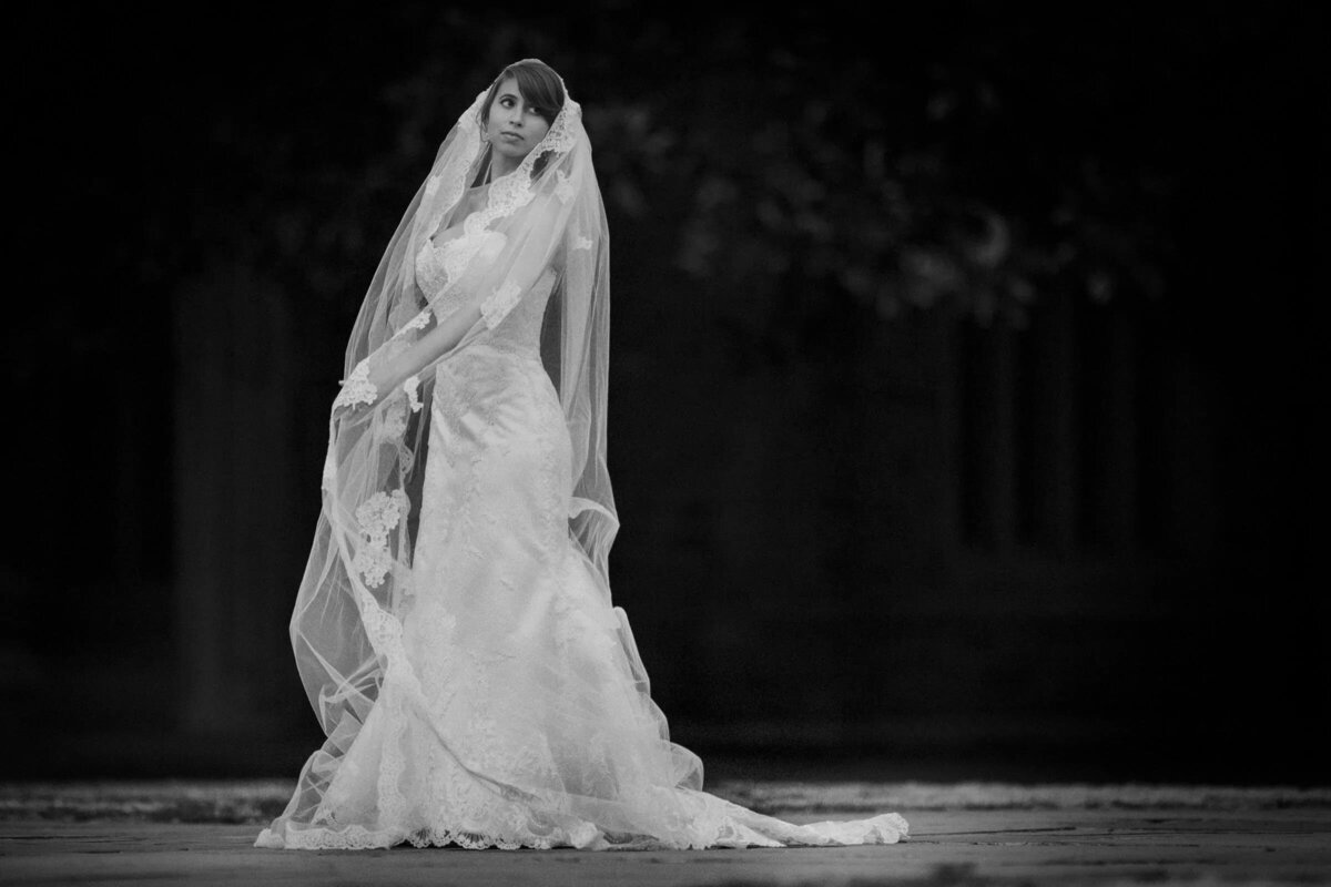 A bride holding her veil and looking back over her shoulder