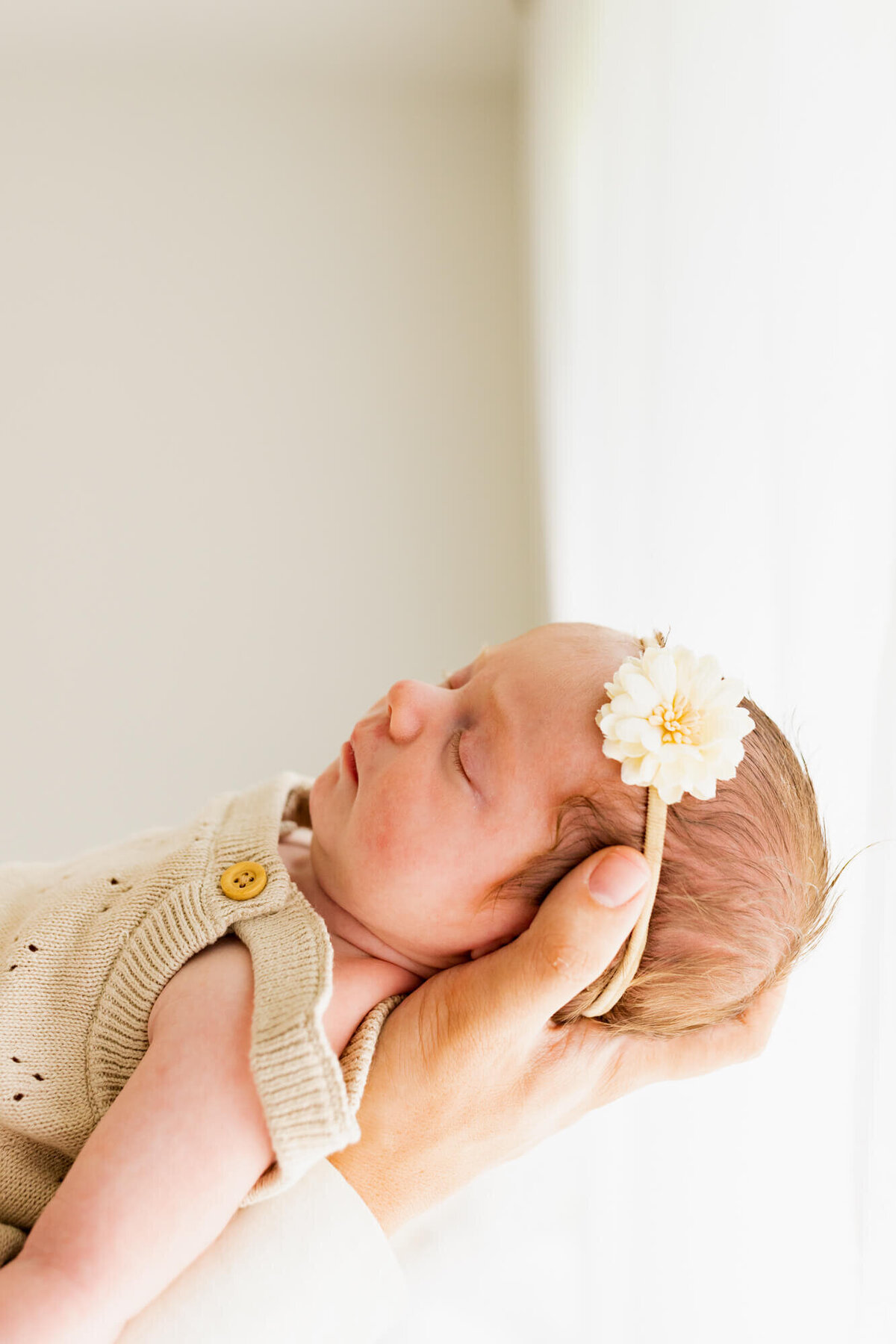 sleeping newborn baby girl in a cream bubble and flower bow