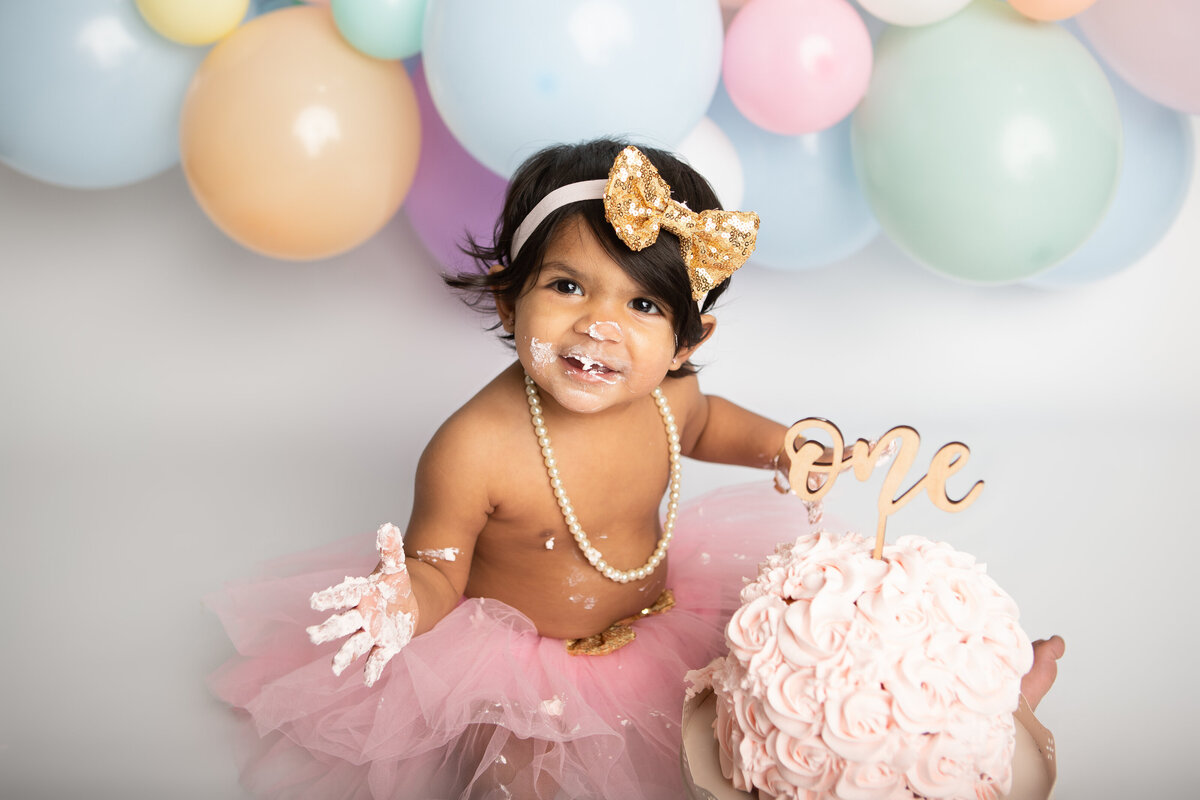 Birthday baby girl with a rainbow balloon garland