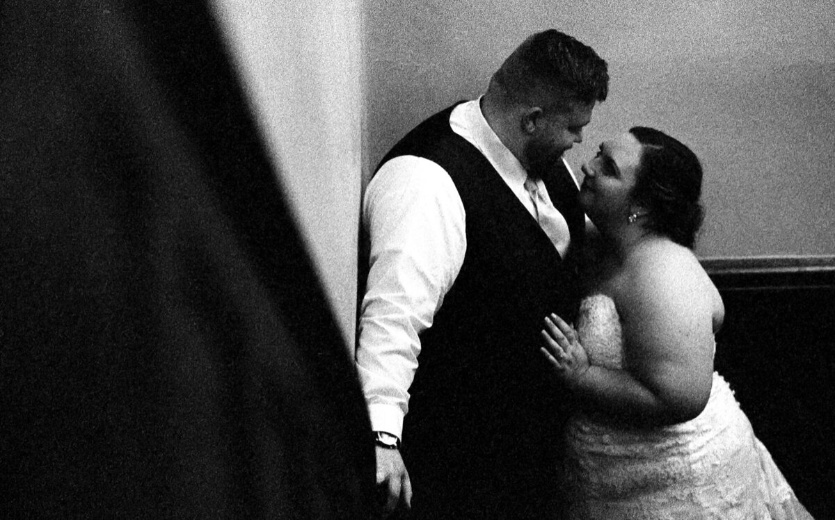 Couple snuggles in the stairwell during their wedding reception