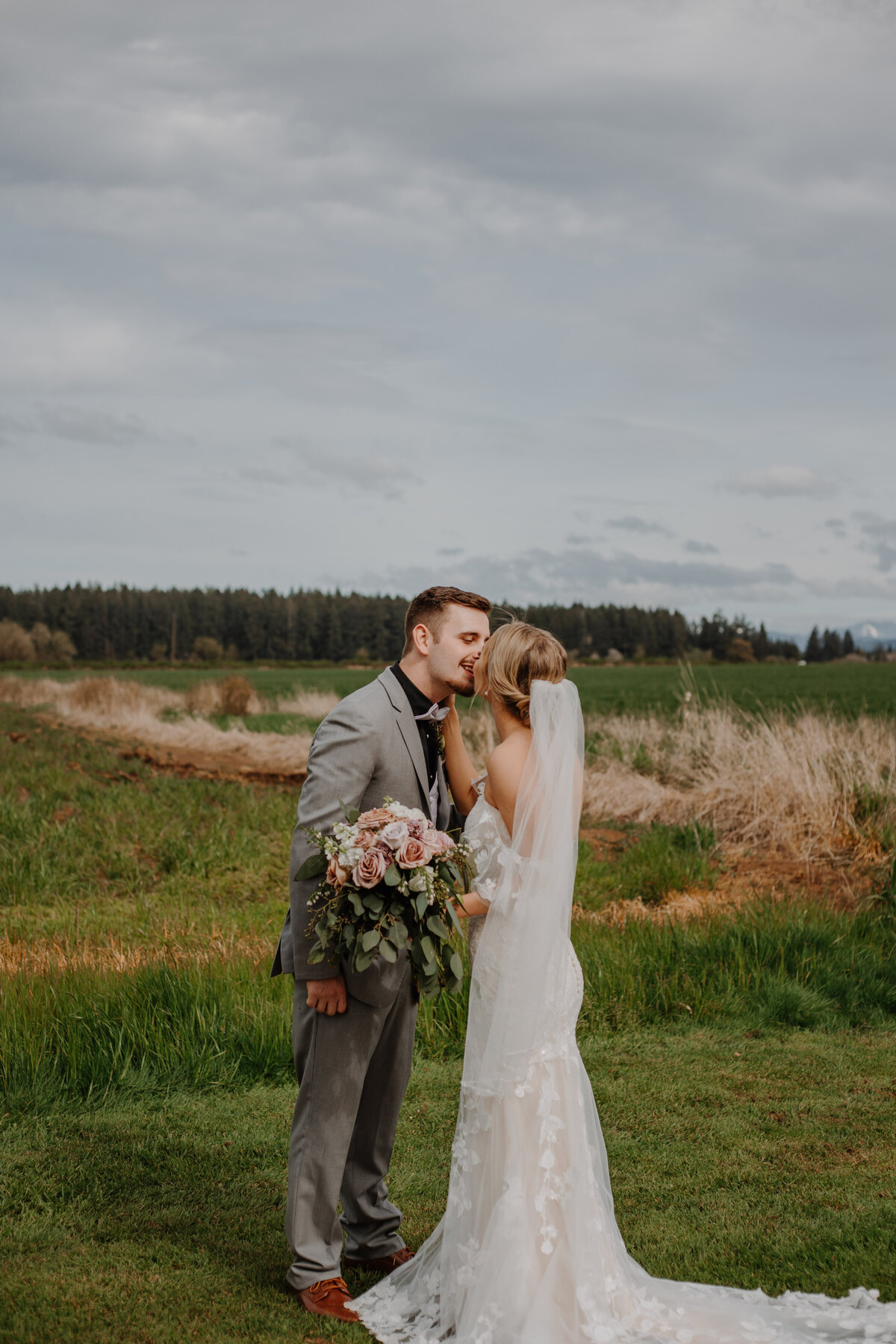 Bride and groom kissing in a grassy field