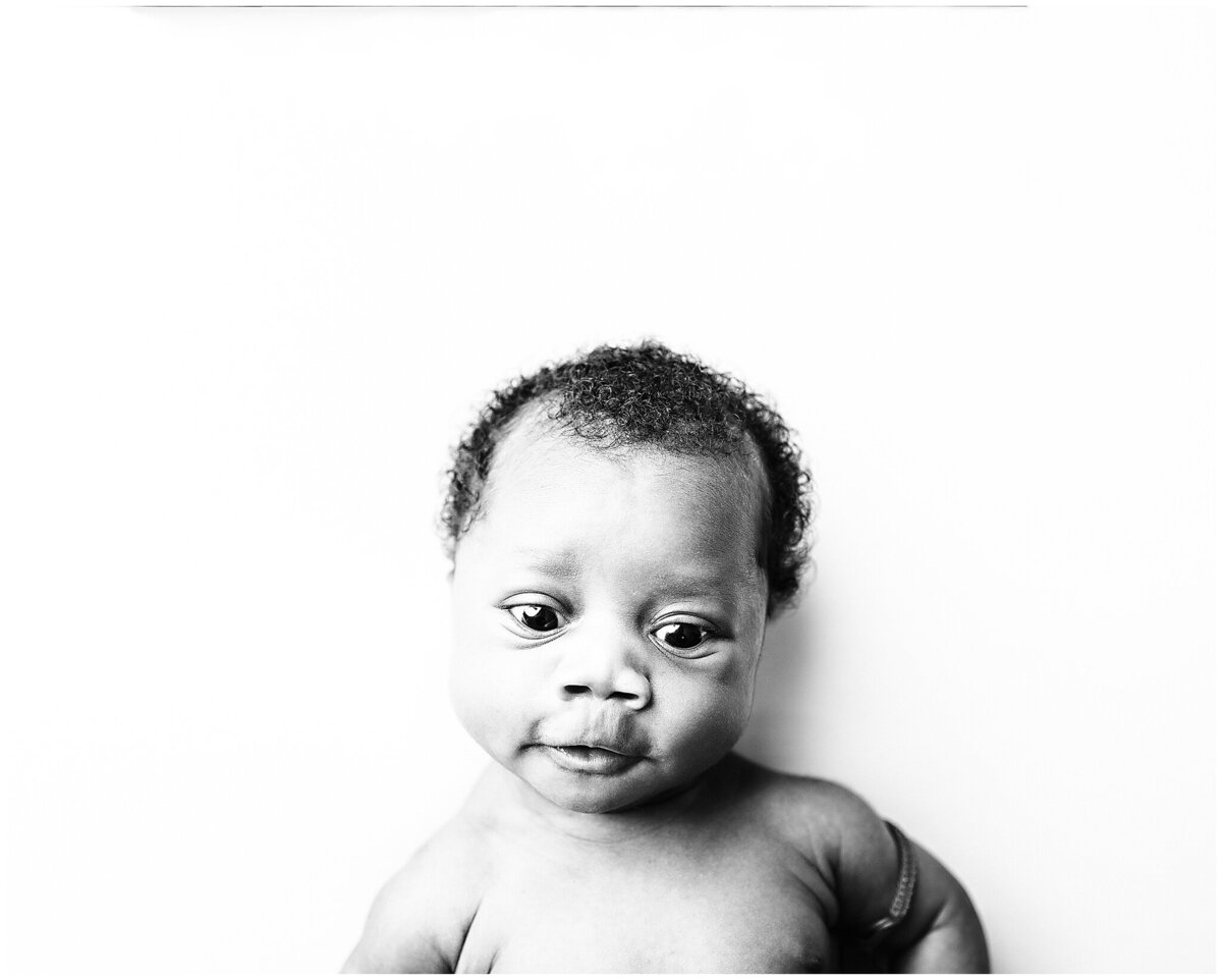 Black and white newborn session with an inquisitive look on his face.