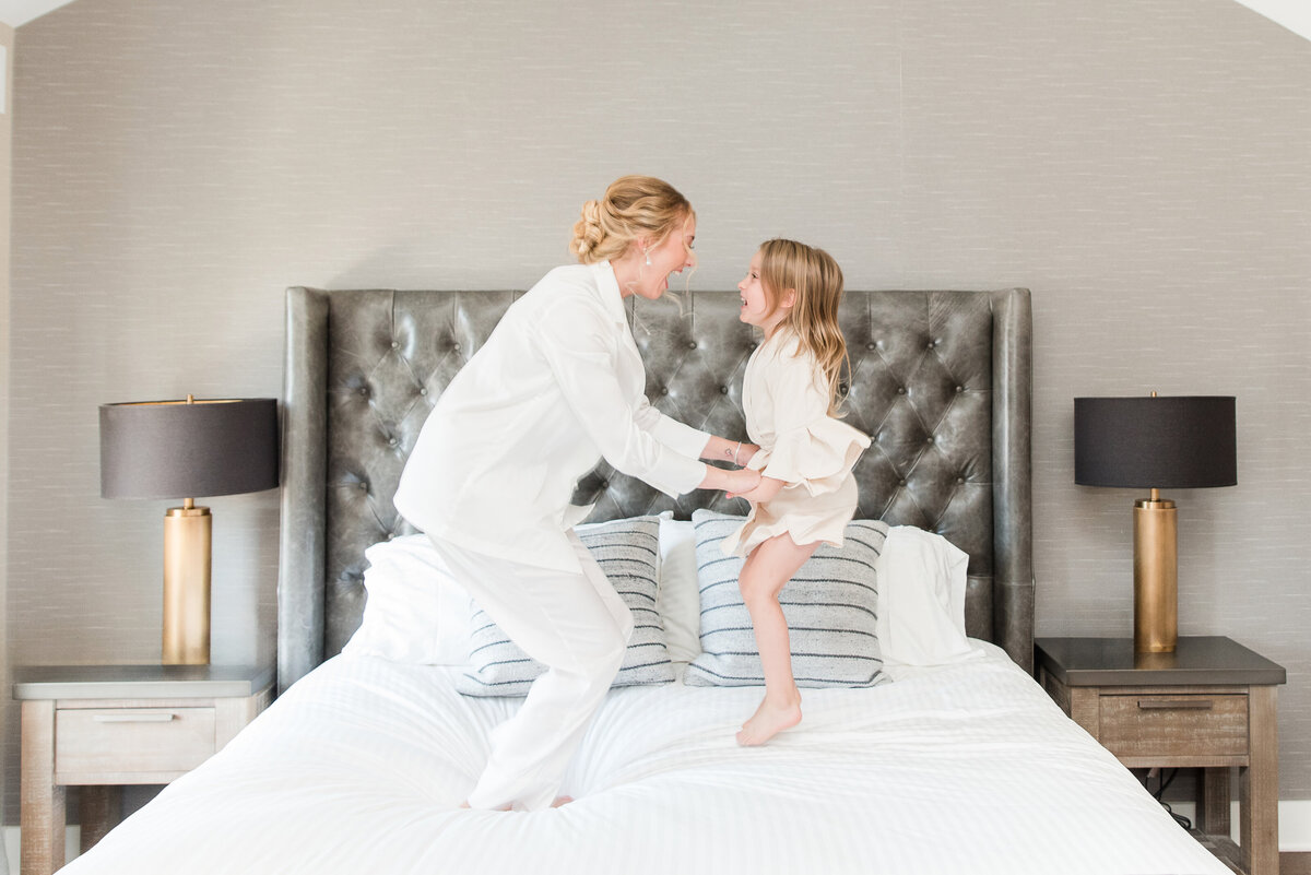 bride and niece jumping on bed on wedding day