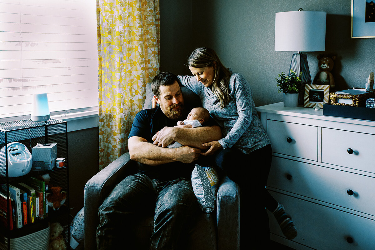 couple hold a baby in a nursery