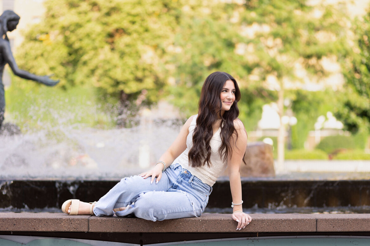 girl sitting on the side of a water fountain