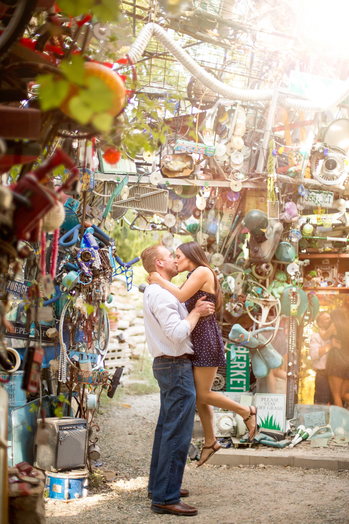Fiancé lifting his fiancée up and kissing her at the Cathedral of Junk in Austin, Texas.
