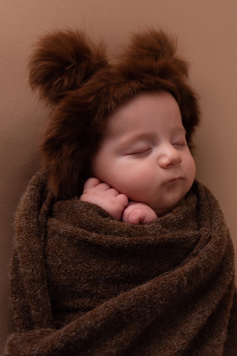 Newborn baby snugly warapped with his warm teddy ears