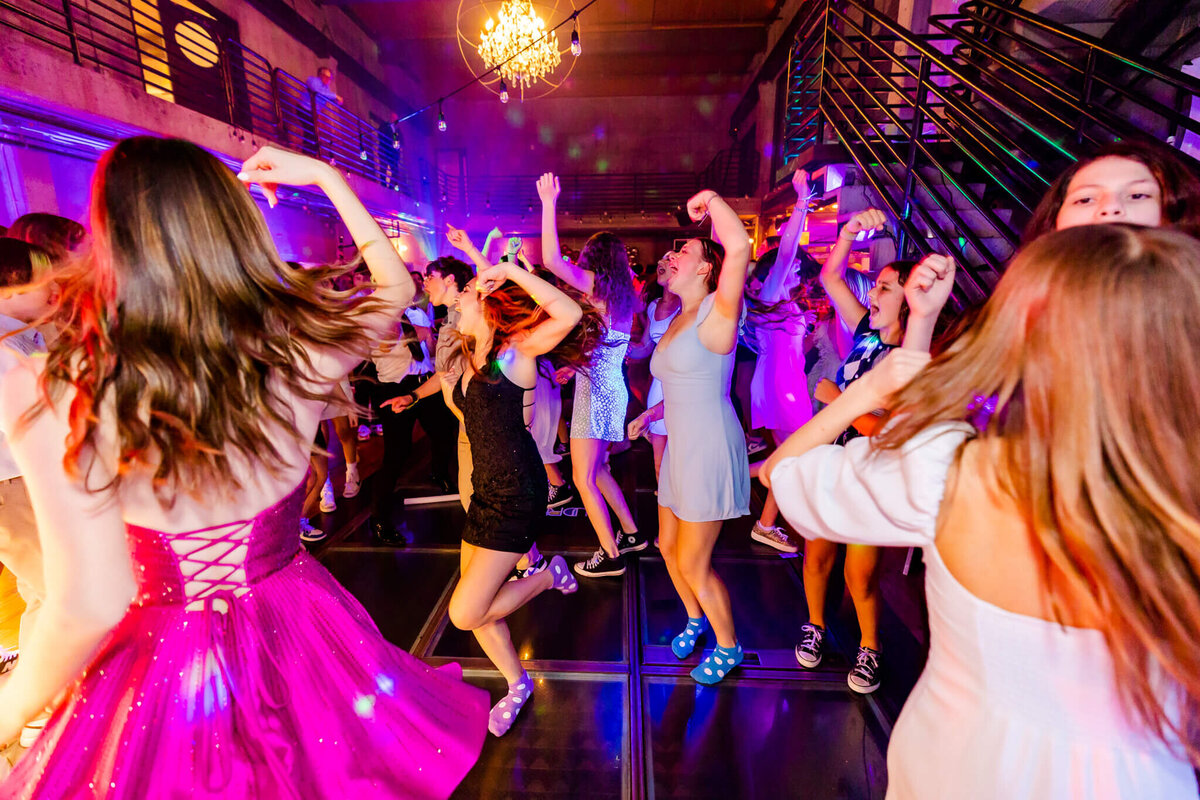 Teen girls dance on a dance floor in dresses