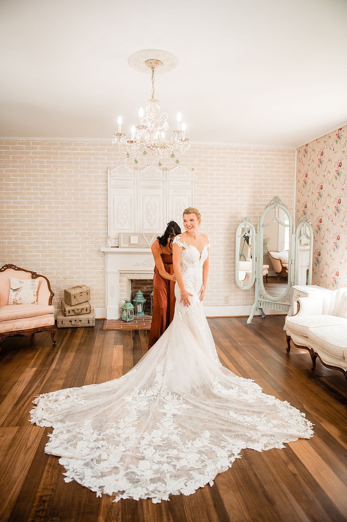 Mother of bride helping button her daughters wedding dress in an elegant bridal suite