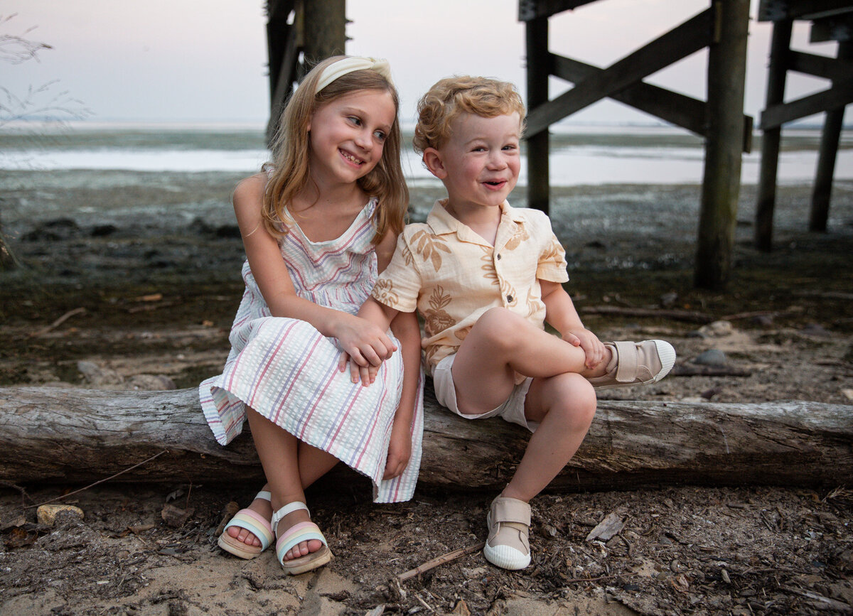 Two smiling siblings giggle during their photoshoot while Ingrid Berrios, their photographer, makes them laugh in Harford County, Maryland