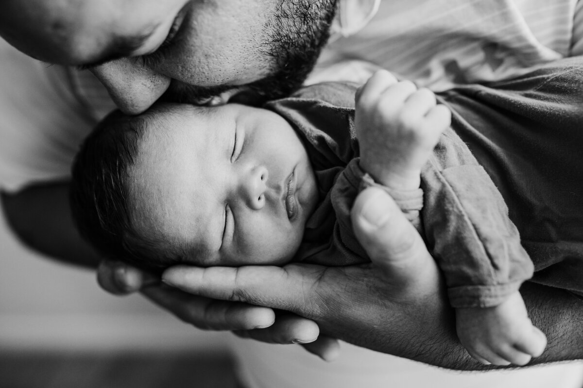 Newborn Photographer, Dad holds baby in hands and reaches down to kiss him