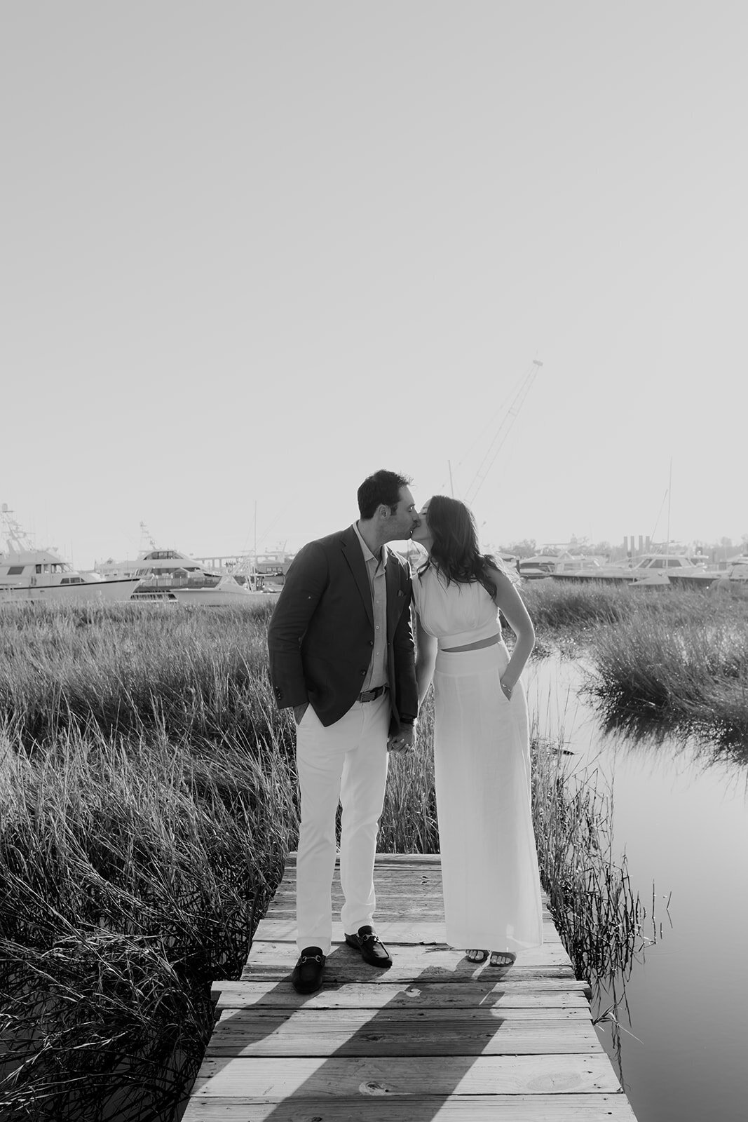 Black and white photo of Couple kissing on pier at Ashley River