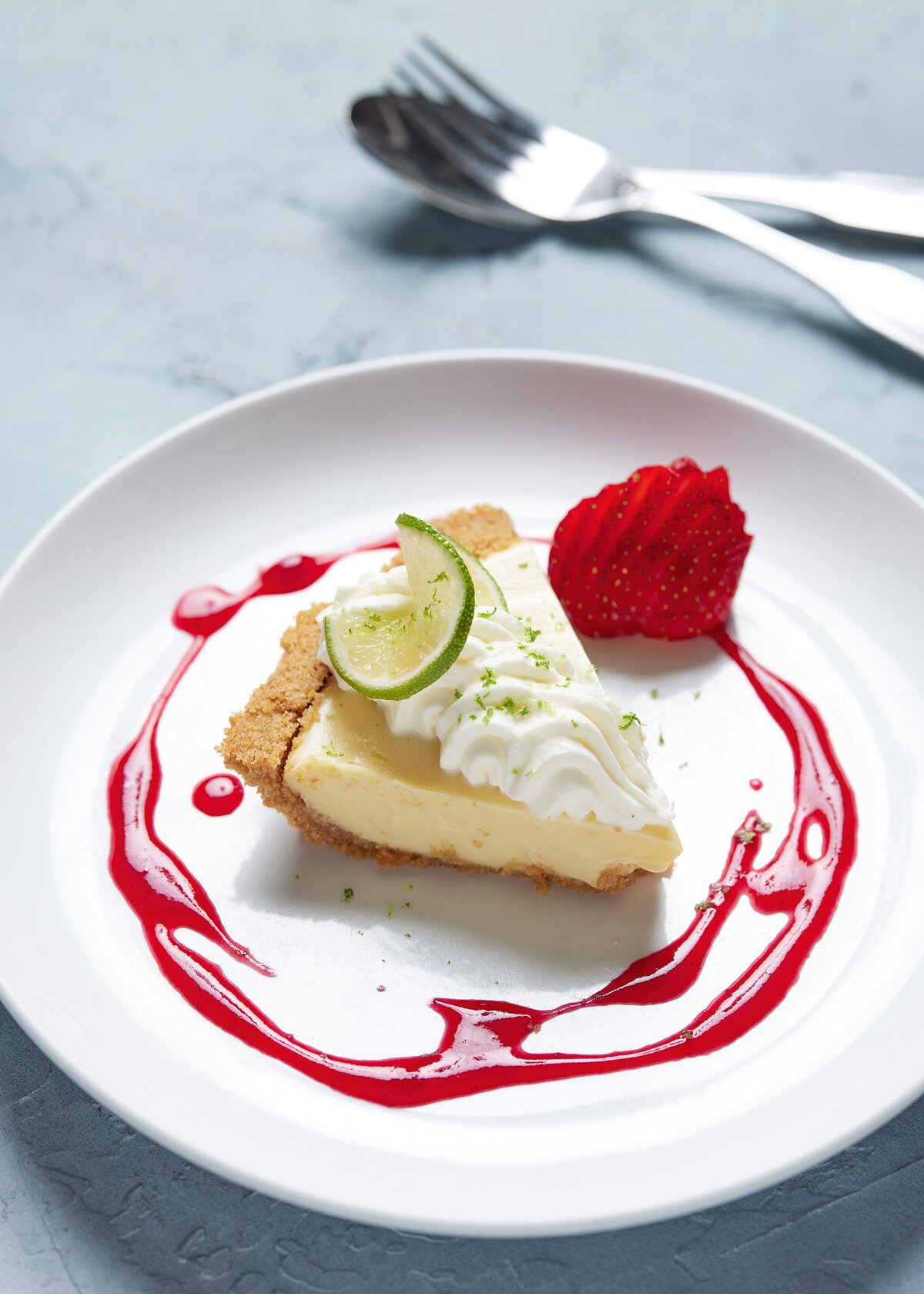 A piece of key lime pie with a fruit sauce