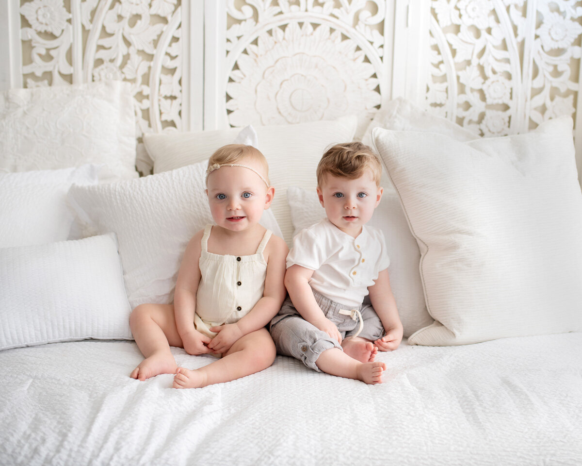 Family session of siblings sitting on a bed