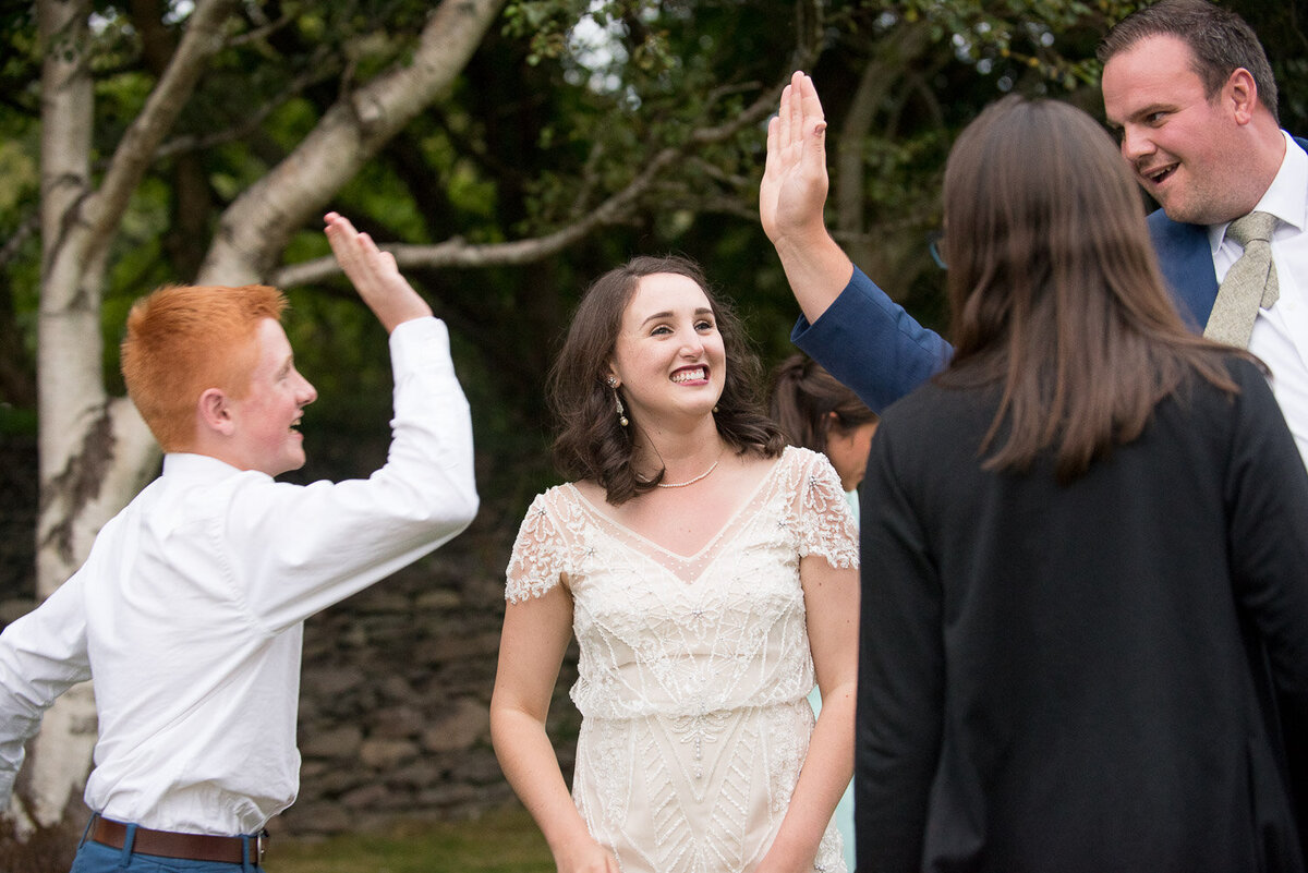 bride in vintage wedding dress watching two wedding guests doing a high five at Castlecove House