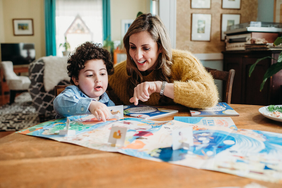 curly haired boy plays board game with mom