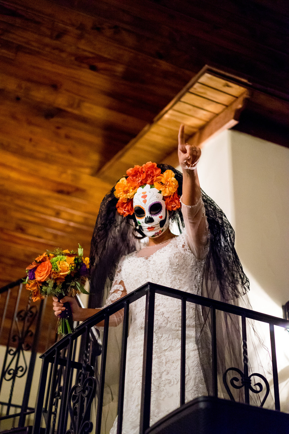 Bride wearing a dia de los muertos mask during reception at Halloween wedding to honor day of the dead at Marquardt Ranch