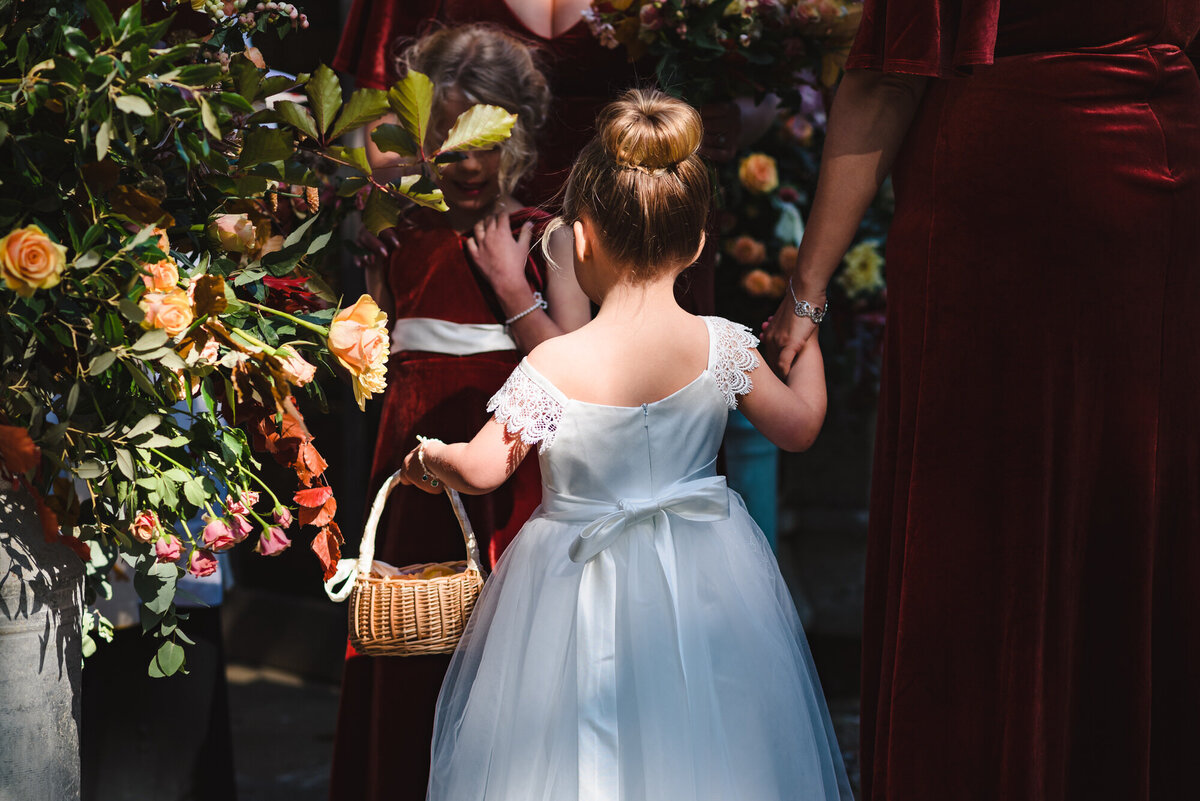 Flower girl holding bridesmaids hand and her flower basket
