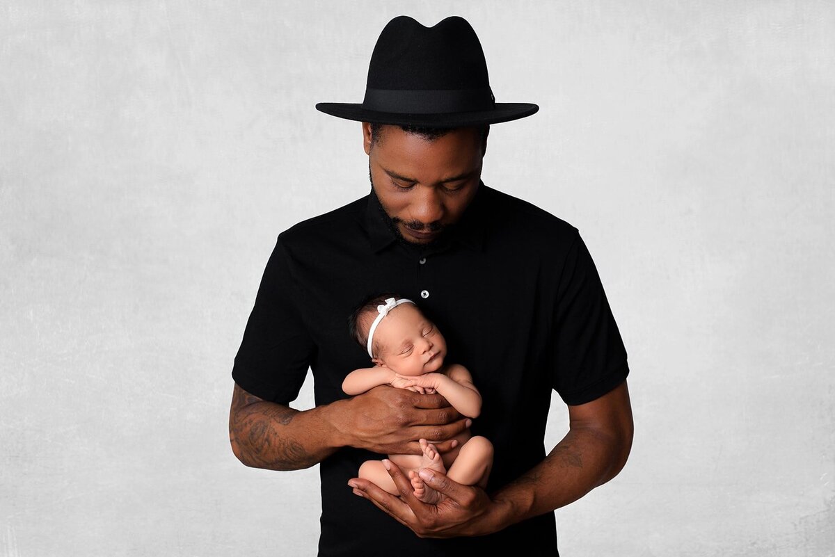 Father in black hat holding mixed race baby girl for Vancouver in-home photo session