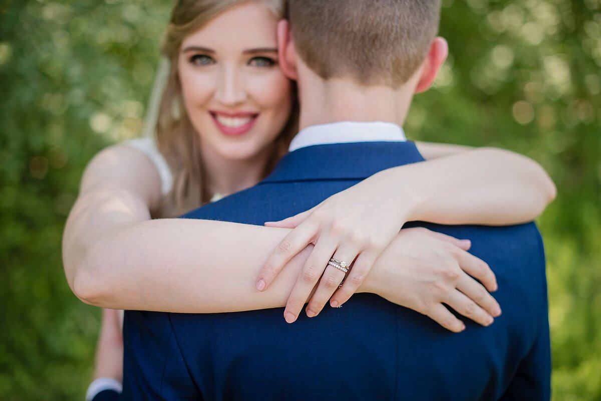 bride looking over grooms shoulders with ring hand in focus