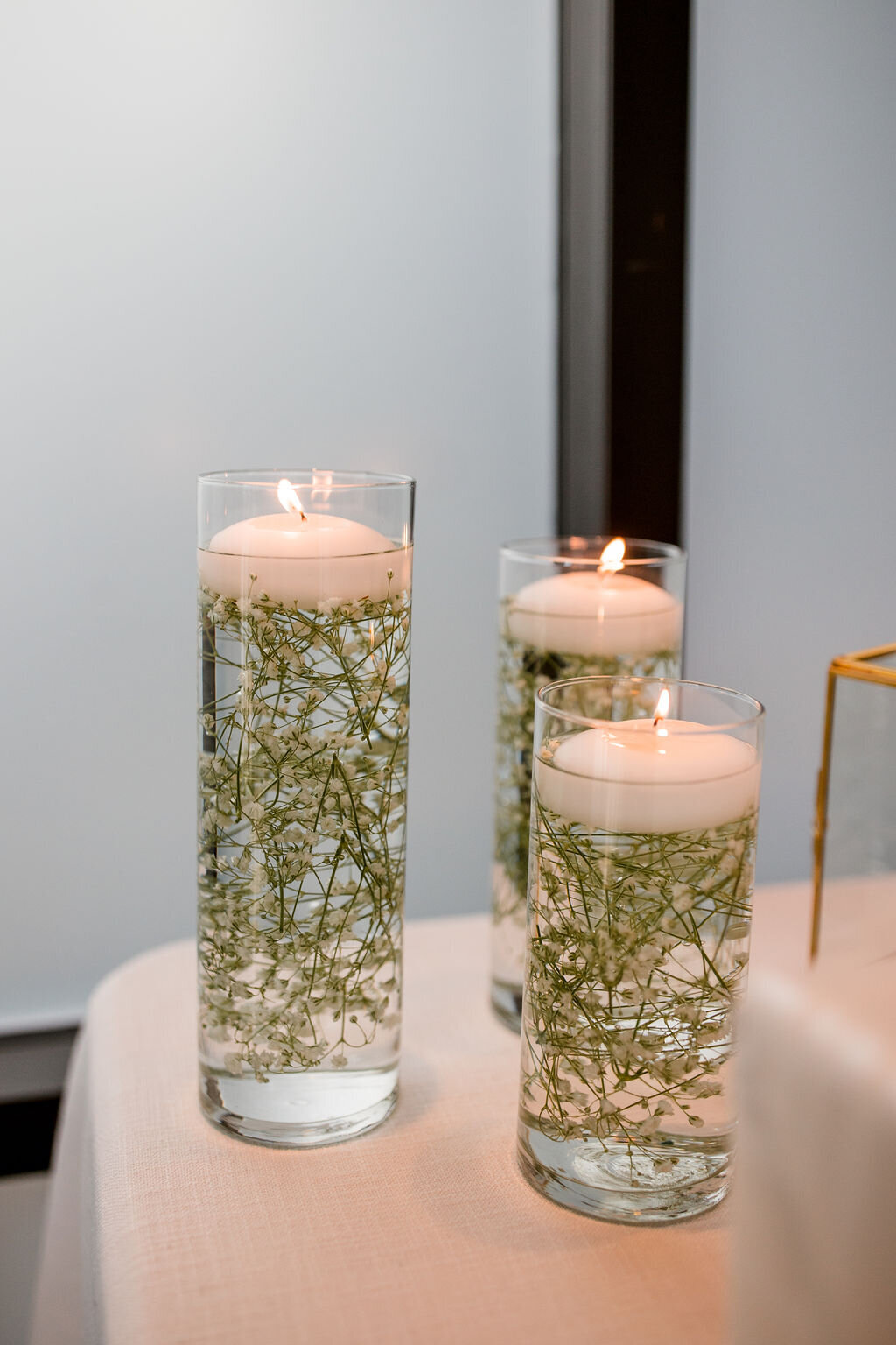 Three cylinder vases mixed sizes filled with baby's breath and water with floating candle