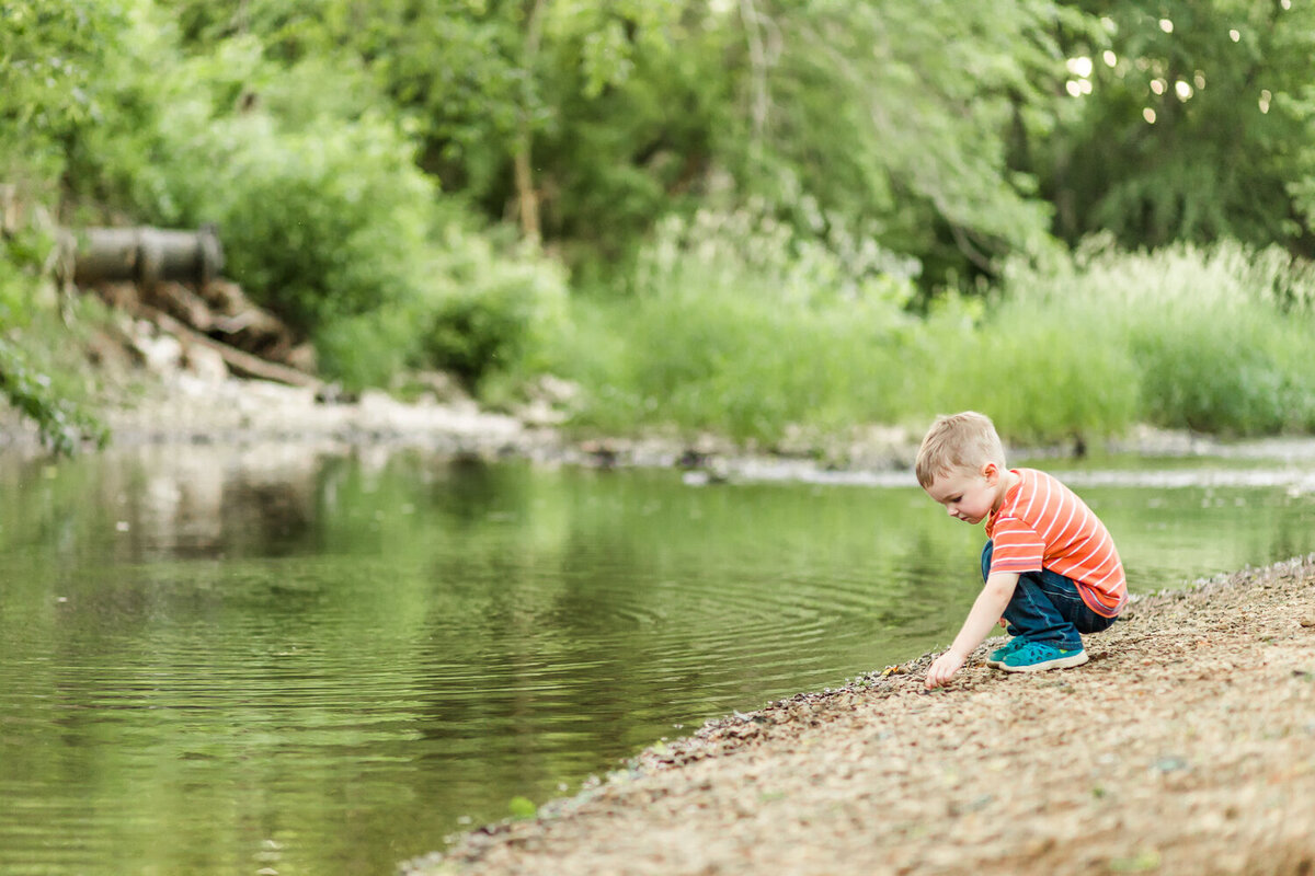 boy collecting rocks by the creek