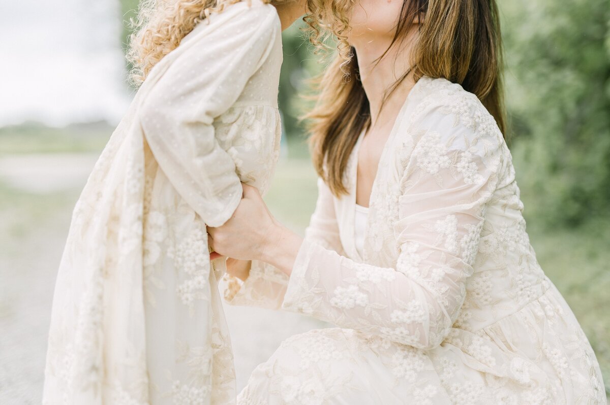 Cropped photograph that shows mom and daughter's hands holding and leaning in for a kiss