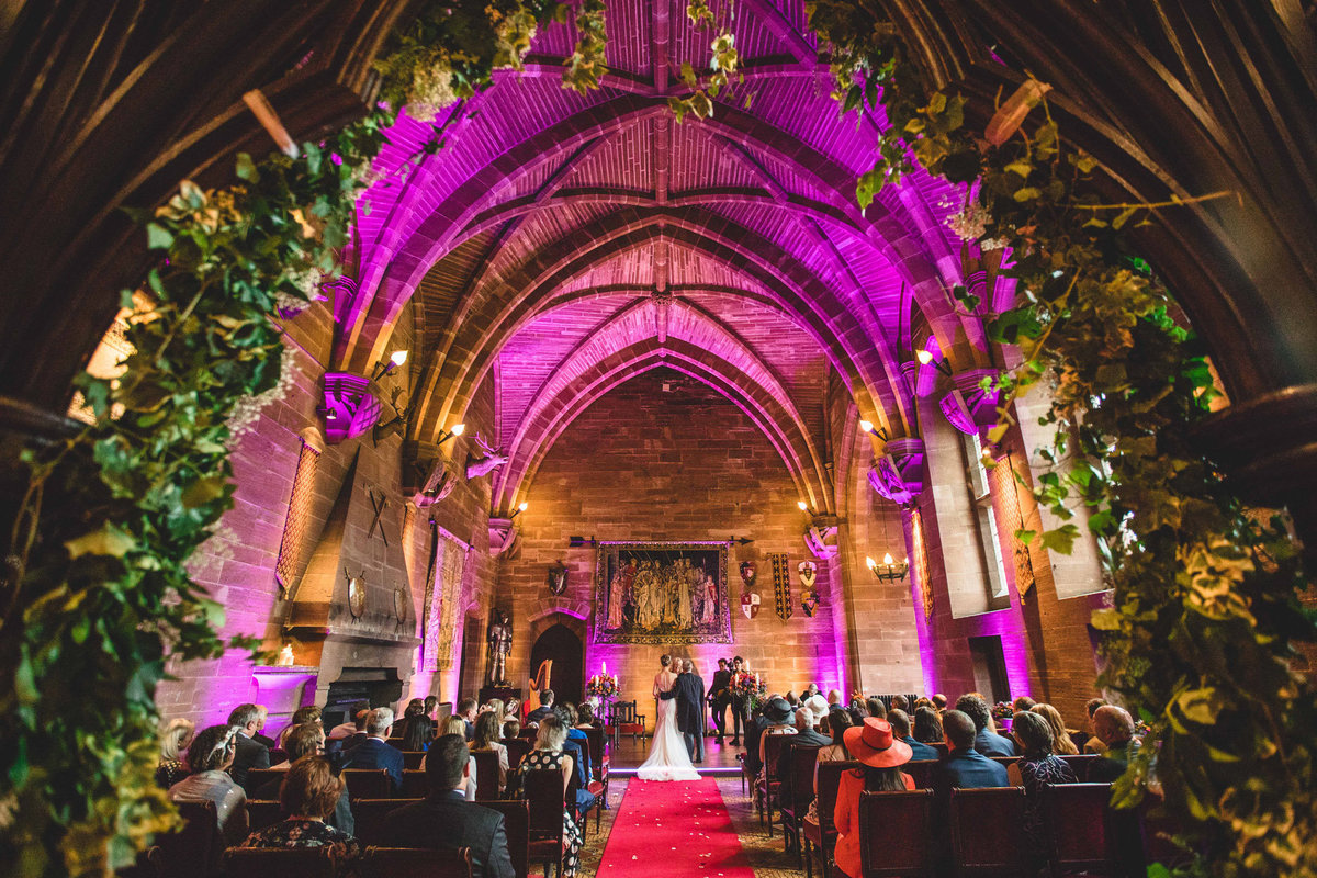 the chapel at peckforton castle lit up with pink during the wedding ceremony