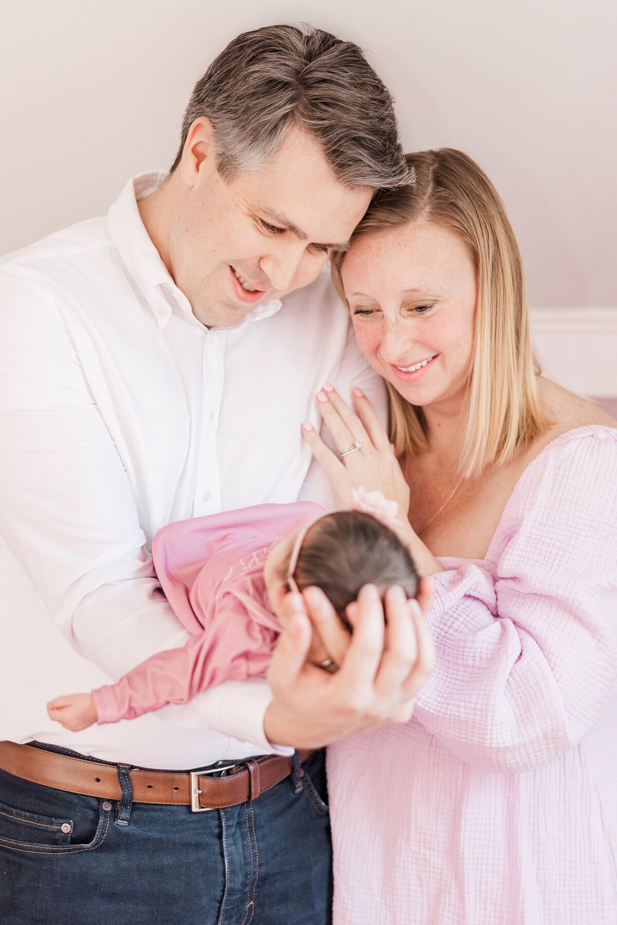 New parents smiling at their baby girl in an Alexandria lifestyle newborn session