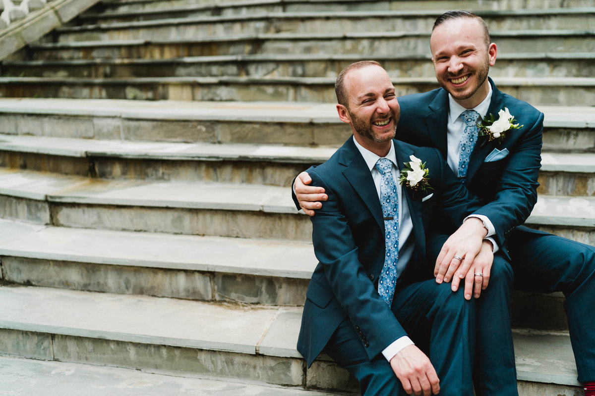 Same sex couple laughs together in a portrait on Airlie's Spanish Steps
