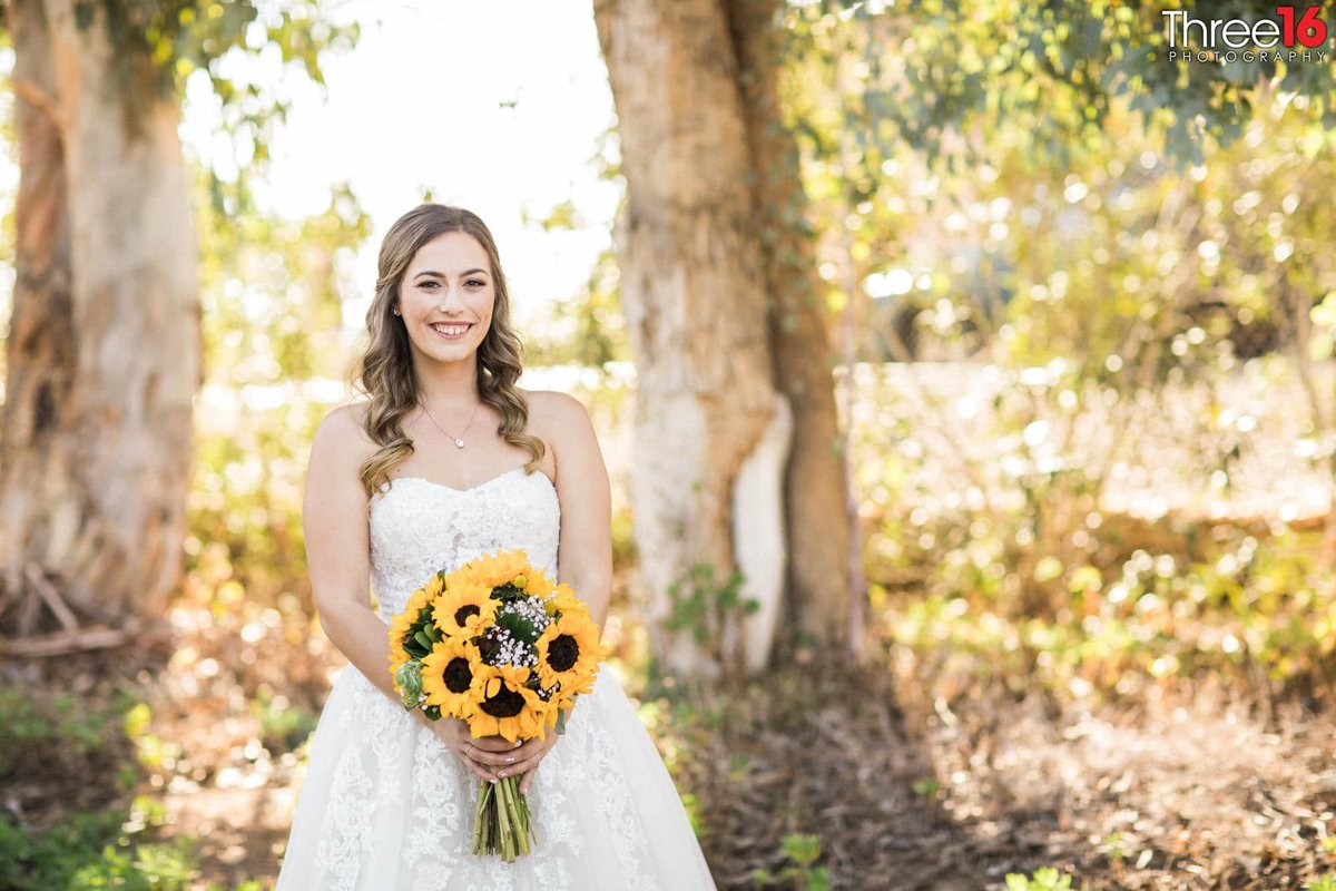 Bride posing in the garden with her sunflower bouquet